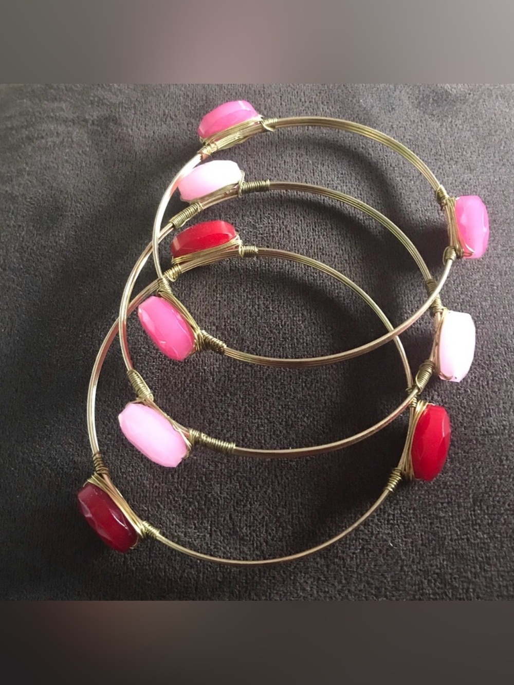 Set of 3 goldtone fashion bangles with red, light pink, and dark pink stones